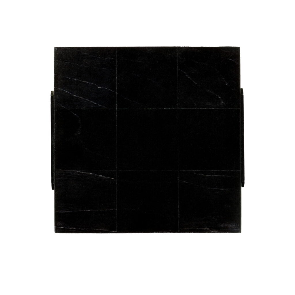 Wall sculpture titled S-025 by Richard Figueras, a 7-1/2 x 7-3/4 x 7/8 inch birch plywood piece painted with black acrylic paint, showing a grid-like pattern of nine square sections with a subtle wood grain texture.